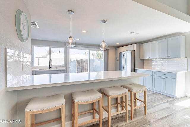 kitchen featuring tasteful backsplash, a kitchen bar, freestanding refrigerator, and a sink