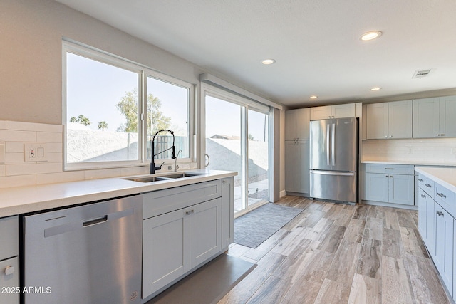 kitchen featuring visible vents, light wood finished floors, a sink, appliances with stainless steel finishes, and light countertops