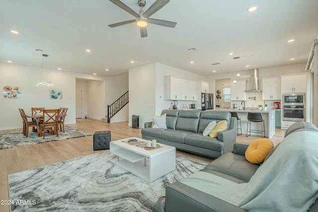 living room featuring ceiling fan, light wood-type flooring, and sink