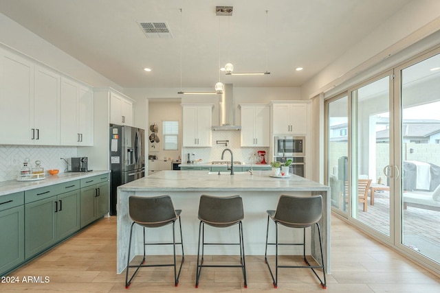 kitchen featuring decorative light fixtures, tasteful backsplash, a healthy amount of sunlight, and wall chimney range hood