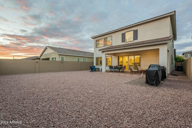 back house at dusk featuring a patio area