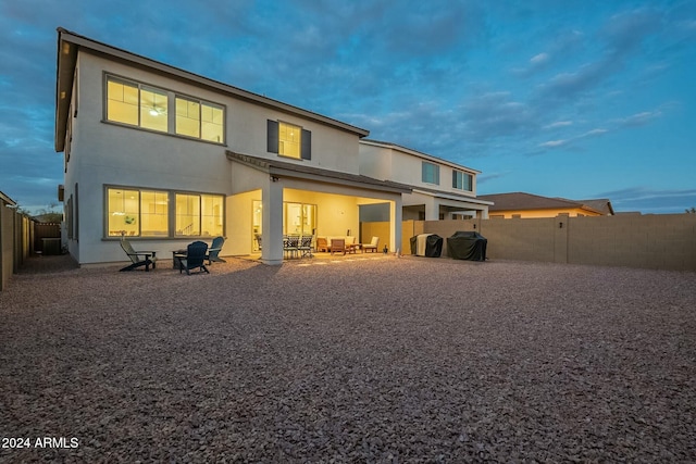 back house at dusk featuring a patio