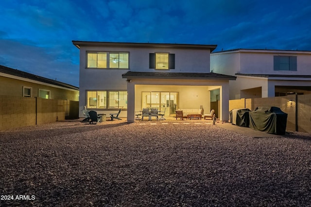 back house at dusk featuring outdoor lounge area and a patio