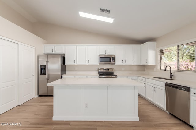 kitchen with stainless steel appliances, sink, lofted ceiling, and a center island