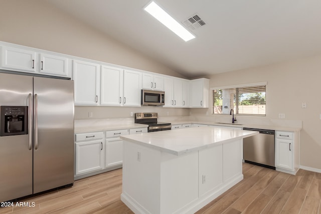 kitchen with lofted ceiling, white cabinetry, stainless steel appliances, and light wood-type flooring