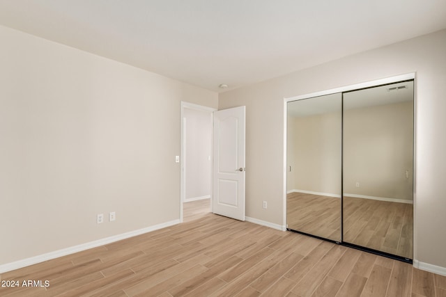 unfurnished bedroom with light wood-type flooring and a closet