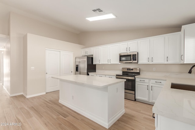 kitchen featuring sink, lofted ceiling, white cabinets, appliances with stainless steel finishes, and a center island