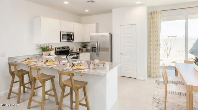 12438 E Verbina Ln, Florence, AZ 85132 - kitchen featuring appliances with stainless steel finishes, a peninsula, white cabinets, a kitchen bar, and recessed lighting
