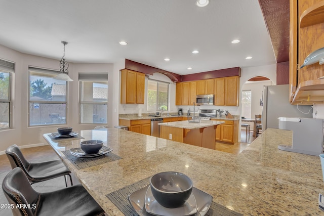 2642 S Joplin, Mesa, AZ 85209 - kitchen with stainless steel appliances, arched walkways, light stone countertops, a kitchen bar, and a center island