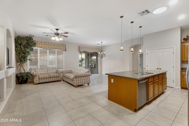 kitchen with dishwasher, decorative light fixtures, a center island with sink, ceiling fan with notable chandelier, and dark stone countertops