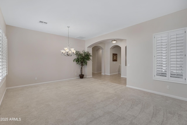 unfurnished room featuring a notable chandelier and light colored carpet