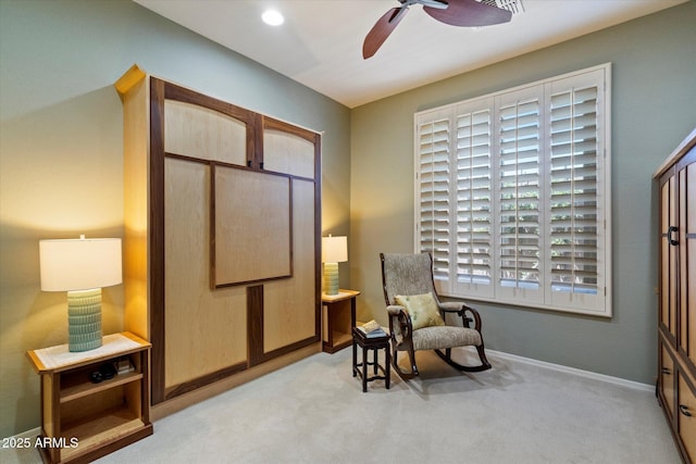living area featuring ceiling fan, baseboards, and carpet