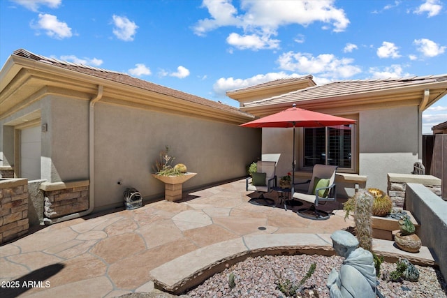 back of house featuring a tile roof, a patio area, and stucco siding