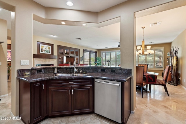 kitchen with dark brown cabinetry, visible vents, stainless steel dishwasher, a sink, and an inviting chandelier