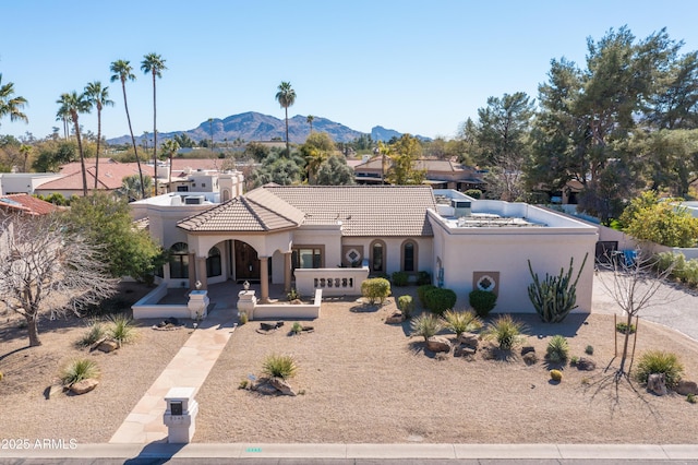 mediterranean / spanish-style home featuring a tile roof, a mountain view, and stucco siding