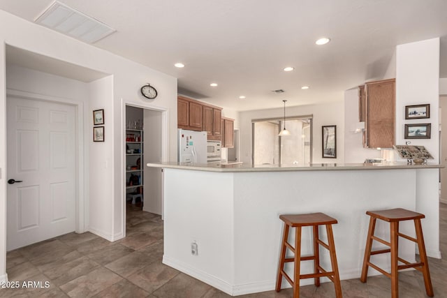kitchen with visible vents, brown cabinets, recessed lighting, white appliances, and a peninsula
