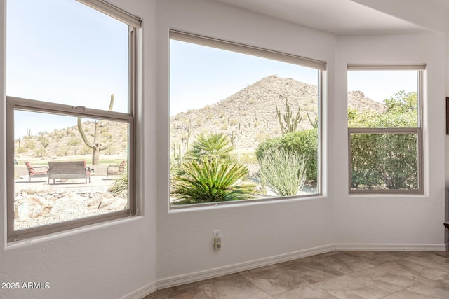 unfurnished room with a mountain view and baseboards