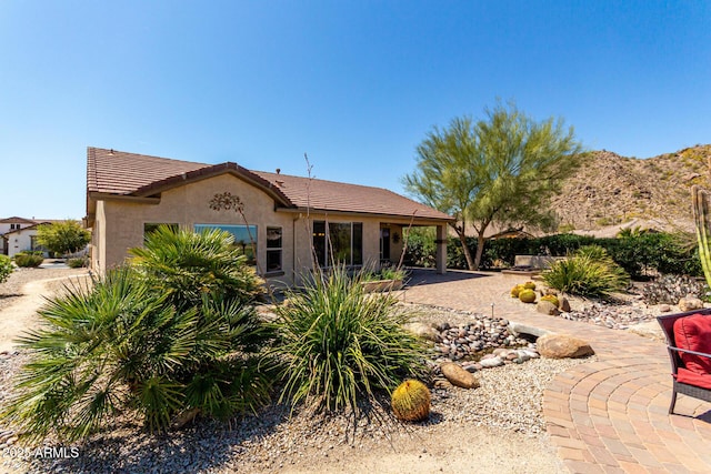 exterior space featuring a patio, a tiled roof, and stucco siding
