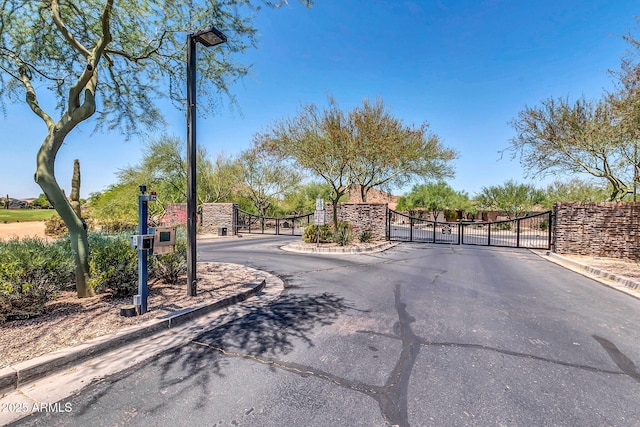 view of street with a gate, curbs, and a gated entry