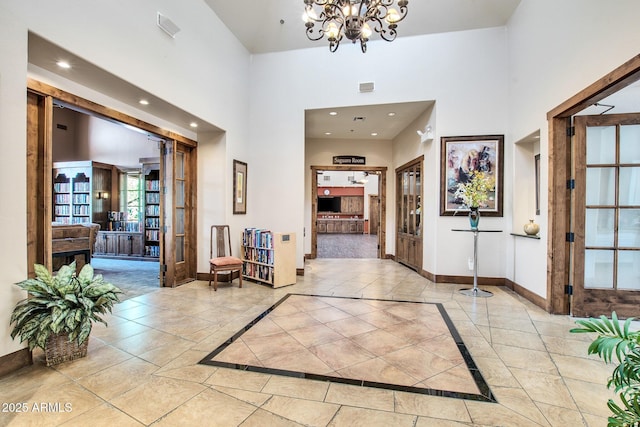 foyer featuring recessed lighting, baseboards, a notable chandelier, and a high ceiling