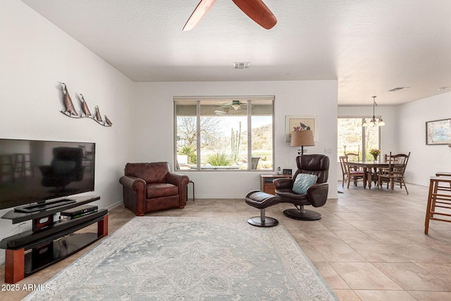 sitting room with light tile patterned floors, ceiling fan with notable chandelier, visible vents, and a wealth of natural light