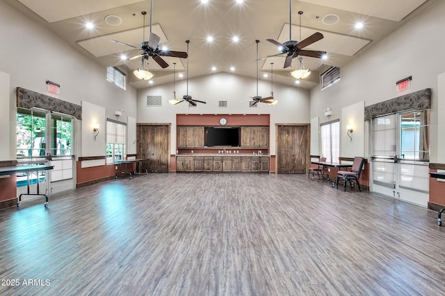 living room with wood finished floors, visible vents, a towering ceiling, and ceiling fan