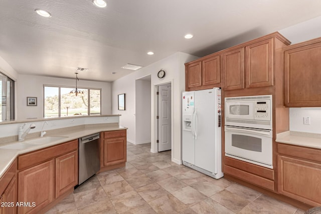 kitchen with white appliances, visible vents, an inviting chandelier, a sink, and light countertops