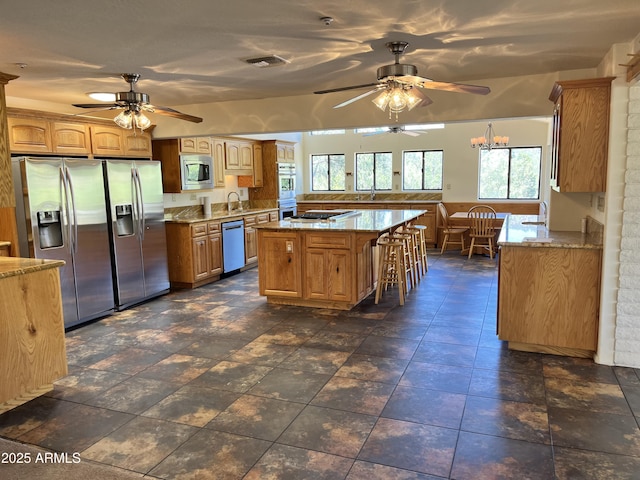 2160 S Moonlight Dr, Star Valley, AZ 85541 - kitchen with appliances with stainless steel finishes, a ceiling fan, light stone countertops, a kitchen bar, and a kitchen island