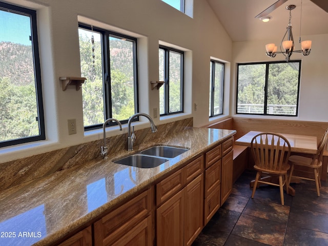 2160 S Moonlight Dr, Star Valley, AZ 85541 - kitchen with a chandelier, brown cabinetry, light stone counters, decorative light fixtures, and lofted ceiling