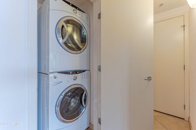 laundry area featuring stacked washer / drying machine and light tile patterned floors