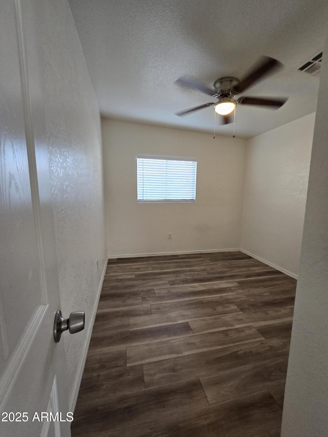 unfurnished room featuring a textured ceiling, ceiling fan, and dark wood-type flooring