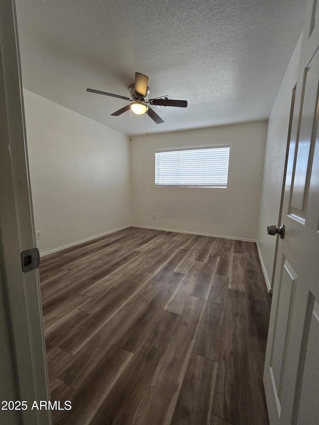 empty room featuring ceiling fan, dark hardwood / wood-style flooring, and a textured ceiling