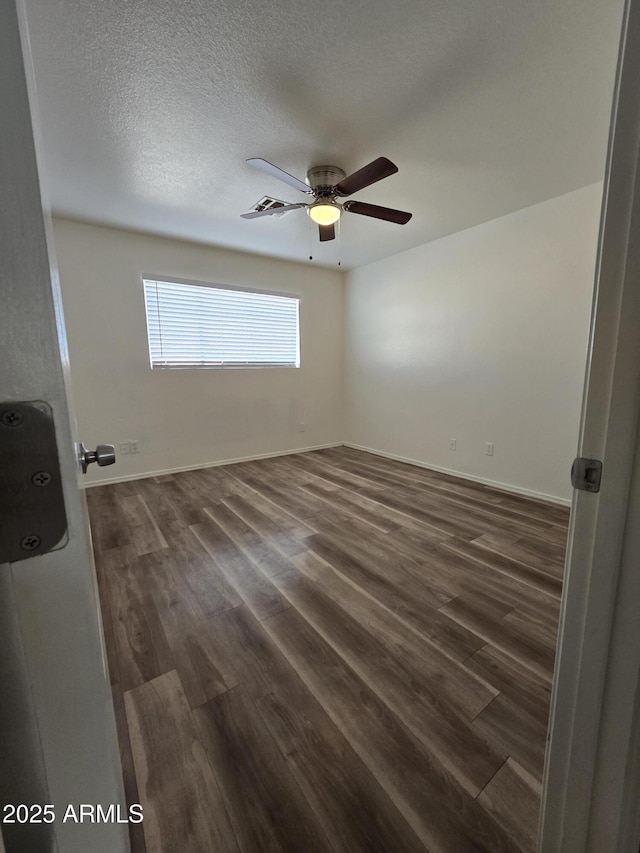 empty room featuring ceiling fan, dark hardwood / wood-style flooring, and a textured ceiling