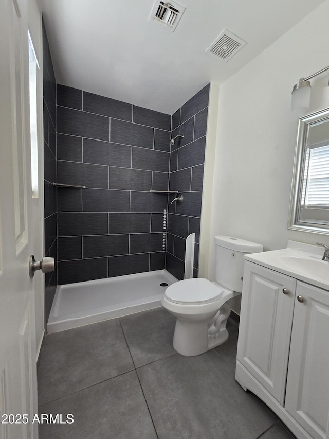 bathroom featuring a tile shower, vanity, and toilet