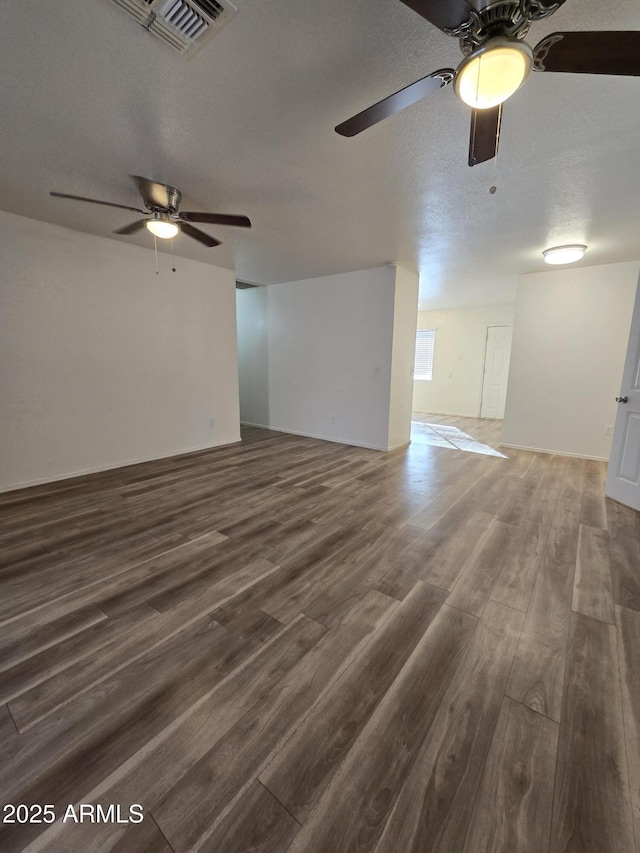 unfurnished living room featuring a textured ceiling, ceiling fan, and dark wood-type flooring