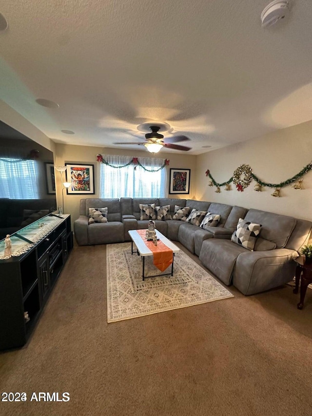 living room with ceiling fan, a textured ceiling, and dark colored carpet