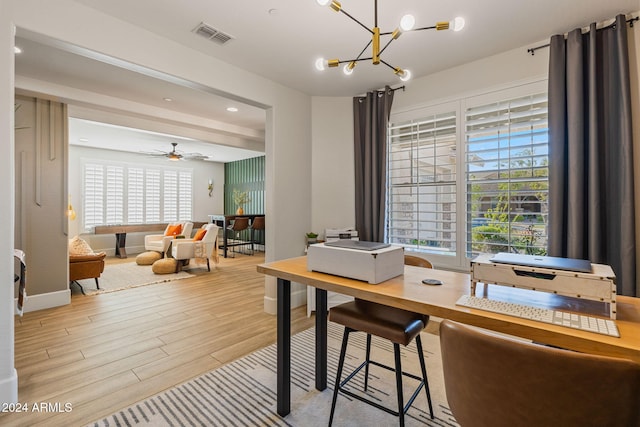 office with light hardwood / wood-style floors, a wealth of natural light, and ceiling fan with notable chandelier