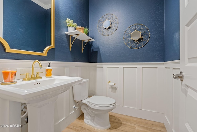 bathroom featuring toilet, ornamental molding, and hardwood / wood-style flooring