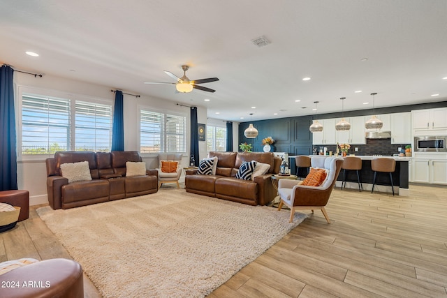 living room with light hardwood / wood-style flooring and ceiling fan