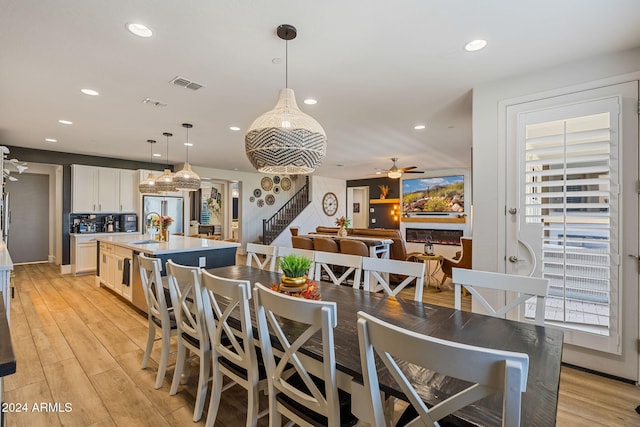 dining area with sink, light hardwood / wood-style floors, and ceiling fan