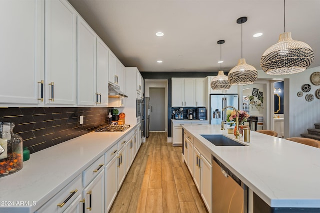 kitchen featuring light hardwood / wood-style flooring, stainless steel appliances, sink, pendant lighting, and white cabinets