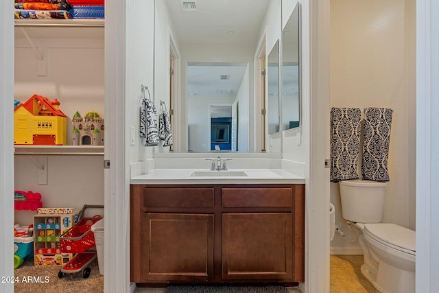 bathroom with toilet, vanity, and tile patterned flooring