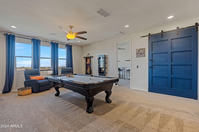 rec room with pool table, a barn door, a textured ceiling, ceiling fan, and carpet