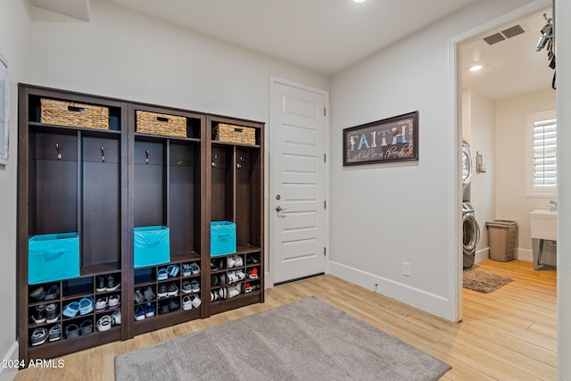 mudroom featuring hardwood / wood-style floors and stacked washing maching and dryer