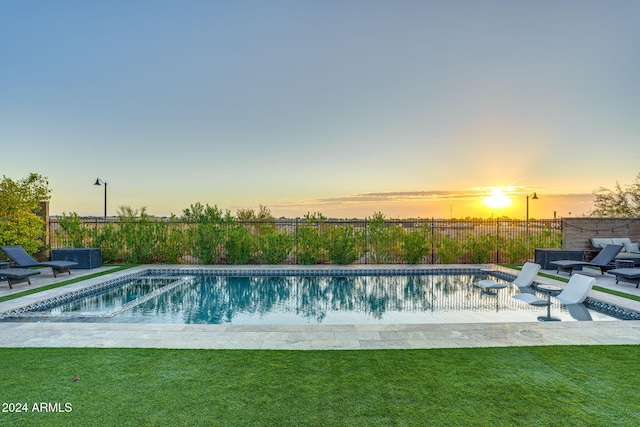 pool at dusk featuring a patio area and a yard