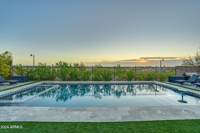 pool at dusk featuring a patio area