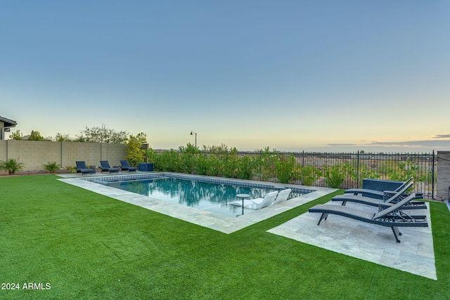 pool at dusk with a yard and a patio area