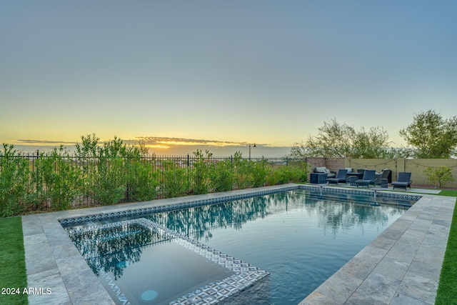 pool at dusk with a patio area