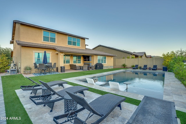 back of property with a yard, a patio, and a fenced in pool