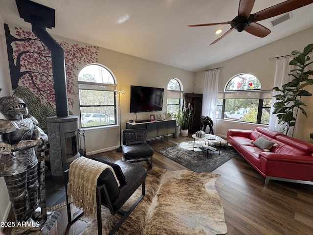 living room with a wood stove, lofted ceiling, dark wood-type flooring, and ceiling fan